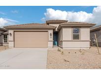 One-story home with tan exterior, two-car garage, and landscaped front yard at 18350 W Poston Dr, Surprise, AZ 85387