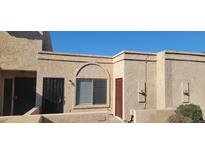 Tan stucco exterior of a condo unit with a window, two doors, and a small bush at 20237 N 21St Ln, Phoenix, AZ 85027