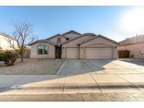 Tan three-car garage home with desert landscaping at 43205 W Askew Dr, Maricopa, AZ 85138