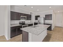 Modern kitchen featuring stainless steel appliances, granite countertops, and dark wood cabinets at 36375 W Picasso St, Maricopa, AZ 85138