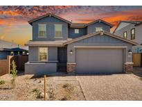 Two-story home featuring blue facade, gabled roof, with a brick driveway leading to an attached two-car garage at 8975 S 168Th Ln, Goodyear, AZ 85338