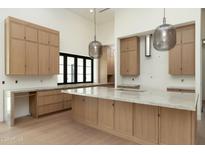 Bright, spacious kitchen featuring an island, light wood cabinetry, and sleek, modern pendant lighting at 23002 N Country Club Trl Trl, Scottsdale, AZ 85255