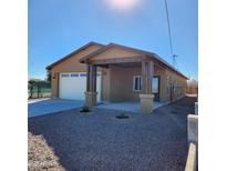 Tan house with a covered porch, white garage door, and gravel driveway at 5647 E Calle Pitaya --, Guadalupe, AZ 85283