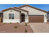 Charming single-story home featuring a well-manicured front yard, a brown garage door and a covered entry way at 17586 W Blue Sky Dr, Surprise, AZ 85387