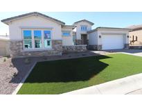 Charming single Gathering home featuring stone accents, a two-car garage, and freshly installed artificial turf at 21627 W Mariposa St, Buckeye, AZ 85396