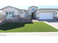 Charming single Gathering home featuring stone accents, a two-car garage, and freshly installed artificial turf at 21627 W Mariposa St, Buckeye, AZ 85396