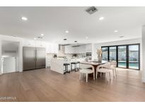 Open-concept kitchen featuring modern white cabinetry, waterfall island and stainless steel appliances at 8531 E San Miguel Ave, Scottsdale, AZ 85250