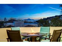 Evening view from a patio with fire pit, chairs, and city skyline in the background at 13503 E Charter Oak Dr, Scottsdale, AZ 85259