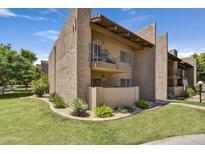 Exterior of a two-story stucco condo featuring a balcony, well-maintained landscaping, and lush green grass at 5525 E Thomas Rd # N1, Phoenix, AZ 85018