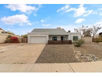 Single-story house with a gray exterior, modern wood accents, and a well-maintained front yard at 12130 N 70Th Ave, Peoria, AZ 85345