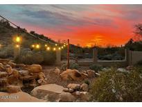 Outdoor patio with rock waterfall and string lights under colorful sky at 20436 N 17Th Pl, Phoenix, AZ 85024