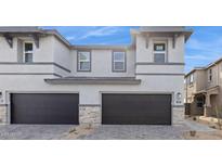 Modern townhome exterior showcasing gray stucco, dark trim, stone accents, and a two-car garage with updated driveway at 5841 E Ringtail Way, Phoenix, AZ 85054