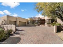 Front view of a Southwestern style home with a large brick driveway and mature trees at 9784 E Miramonte Dr, Scottsdale, AZ 85262