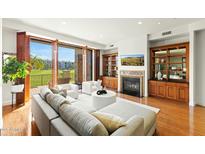 Bright living room with hardwood floors, fireplace, built-ins, and large sliding doors leading to a balcony at 2 E Biltmore Estates Dr # 115, Phoenix, AZ 85016