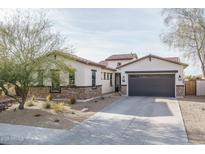 Charming home featuring a gray garage door, desert landscaping, and a mix of stone and stucco finishes at 15312 S 181St Dr, Goodyear, AZ 85338