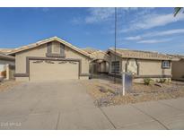 Beige house with two-car garage, landscaping, and a real estate sign at 14426 W Morning Star Trl, Surprise, AZ 85374