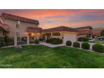 Charming home featuring a green lawn, unique tile roof, manicured bushes and an attached two-car garage at 9734 N 105Th Dr, Sun City, AZ 85351