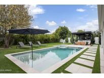 A backyard oasis featuring a pool, spa, outdoor kitchen, and lush landscaping, perfect for relaxation and entertaining at 329 E Belmont Ave, Phoenix, AZ 85020