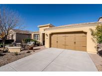 Front view of single-story home with tan colored exterior, two-car garage, and landscaped yard at 392 E Laddoos Ave, Queen Creek, AZ 85140