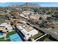 Aerial view of house, pool, and backyard; tennis court and mountain views at 4461 E Flower St, Phoenix, AZ 85018