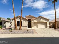 Charming single-story home with a terra cotta tile roof, palm trees, and low maintenance desert landscaping at 18068 W Browning Dr, Surprise, AZ 85374