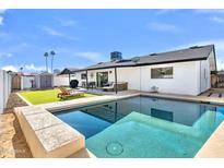 Enjoy this backyard pool with green grass, palm trees, and patio furniture at 3807 N 87Th St, Scottsdale, AZ 85251