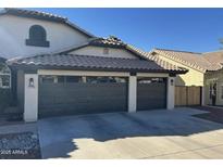 Three-car garage with dark brown doors and a long driveway at 10812 S Coolwater Dr, Goodyear, AZ 85338