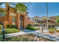 Beautiful condo building with manicured landscaping and walkway leading to a pool area at 14575 W Mountain View Blvd # 11317, Surprise, AZ 85374