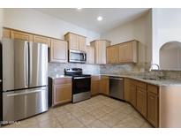 Bright kitchen features stainless steel appliances, tile backsplash, and granite countertops at 14575 W Mountain View Blvd # 11317, Surprise, AZ 85374