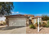 Tan two-story house with a three-car garage and desert landscaping at 13348 W Calavar Cir, Surprise, AZ 85379