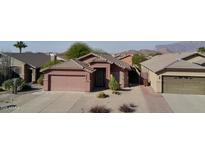 Single-story house with a two-car garage, desert landscaping, and mountain views in the background at 8944 E Red Mountain Ln, Gold Canyon, AZ 85118