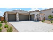 Modern three-car garage home with stone accents and desert landscaping at 9868 S Caballo Dr, Apache Junction, AZ 85120