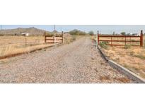 Gravel driveway leading to a ranch style home with wooden gates at 11865 N Allegro Rd, Maricopa, AZ 85139