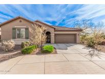 One-story house with tan exterior, landscaped yard, and two-car garage at 1727 N 213Th Dr, Buckeye, AZ 85396