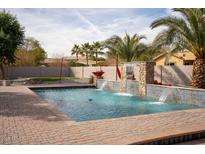 Refreshing swimming pool with a waterfall feature and a spacious patio area at 3410 N 131St Ln, Litchfield Park, AZ 85340