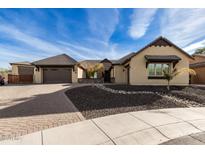 Stunning tan house with a brown roof, brick driveway, and nicely landscaped yard at 7130 W Rowel Rd, Peoria, AZ 85383