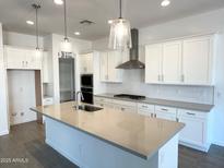 Bright kitchen features white cabinets, stainless appliances, herringbone backsplash, and large center island at 11462 E Utopia Ave, Mesa, AZ 85212