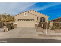 Tan house with a three-car garage and well-manicured landscaping at 6890 W Charter Oak W Rd, Peoria, AZ 85381