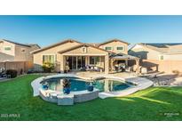 Inviting backyard oasis with sparkling pool, covered patio, and lush landscaping at 44049 W Palo Nuez St, Maricopa, AZ 85138