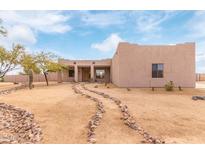 Desert landscape with stucco home, stone pathway, and mature trees at 22605 W Baker Dr, Wittmann, AZ 85361