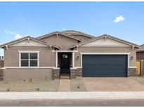 Charming single-story home with a brick driveway, desert landscaping and a dark blue garage door at 4727 N 177Th Dr, Goodyear, AZ 85395