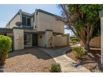 Front view of a light beige, two-story townhome with a walkway and landscaping at 9054 N 51St Ln, Glendale, AZ 85302