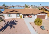 Single story home with lake view, two-car garage, and landscaped yard at 10178 W San Lazaro Dr, Arizona City, AZ 85123