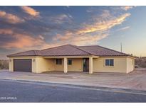 Tan house with tile roof, two-car garage, and front porch at 125 Ironwood Pl, Wickenburg, AZ 85390