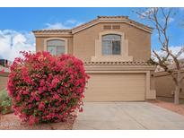 Charming home featuring a neutral color palette, tile roof, an attached two-car garage and blooming bougainvillea at 12474 W Redfield Rd, El Mirage, AZ 85335