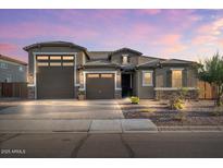 Two-story house with a three-car garage and landscaped front yard at 9925 E Orange Grove St, Florence, AZ 85132