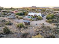 Expansive aerial view of desert property with a modern home, pool, horse facilities, and mountain views at 14235 E Dale Ln, Scottsdale, AZ 85262