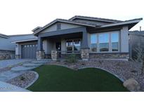 Charming single-Gathering home with a covered porch, stone accents, and a well-manicured front yard at 32496 N 135Th Dr, Peoria, AZ 85383