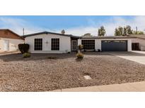 White single story home with a dark gray garage door and rock landscaping at 4639 W Becker Ln, Glendale, AZ 85304