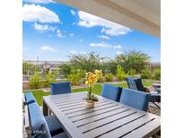 Inviting covered patio with modern furniture and views of the beautifully landscaped backyard and blue sky at 20363 W Coolidge St, Buckeye, AZ 85396